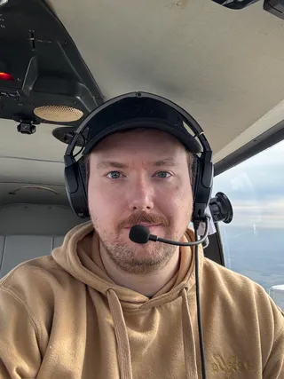 Jeremy at the controls of a small aircraft, wearing an aviation headset